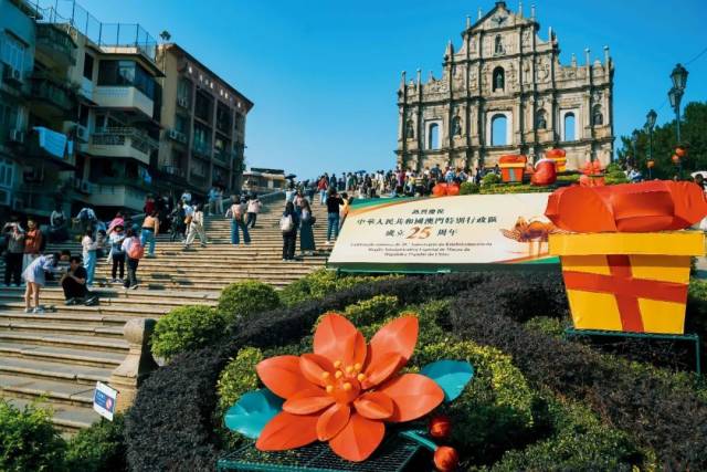 12月5日，澳門大三巴牌坊，“熱烈慶祝中華人民共和國澳門特別行政區成立25周年”的標志吸引游客留影。圖/視覺中國