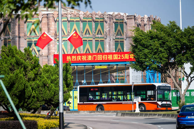 12月17日，車輛從慶祝澳門回歸祖國25周年橫幅旁駛過。新華社記者 朱煒 攝