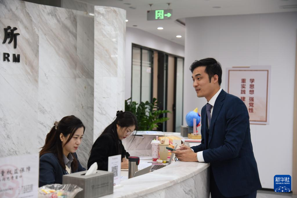 澳門律師阮嘉銳（右）在和同事交談（12月19日攝）。新華社記者 洪澤華 攝