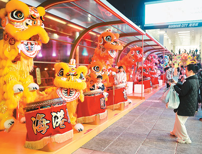 近日在香港維多利亞港畔，游客和醒獅合影。新華社記者 褚萌萌攝