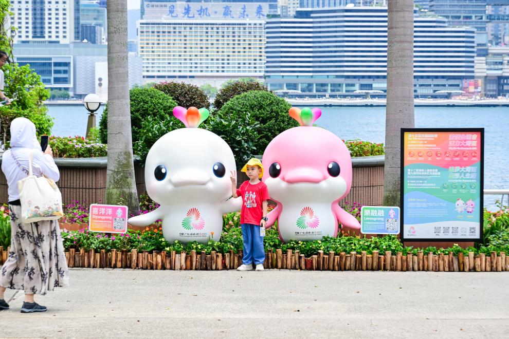 圖為一名兒童在香港金紫荊廣場的第十五屆全國運動會吉祥物旁留影