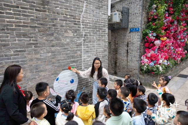 老師在給小朋友介紹十五運吉祥物“喜洋洋”頭上的三色水花背后的含義。