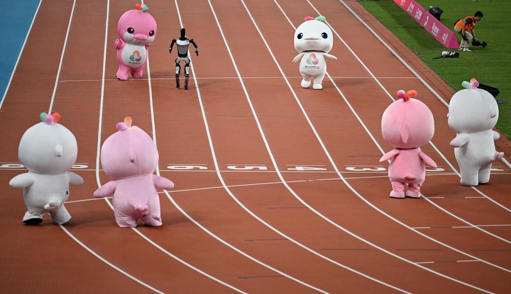 11月17日，在田徑項(xiàng)目賽事開(kāi)始前的暖場(chǎng)活動(dòng)中，機(jī)器人和吉祥物喜洋洋、樂(lè)融融在廣東奧體中心體育場(chǎng)賽跑。