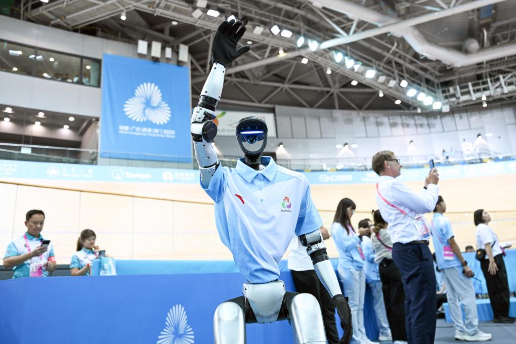 11月13日，參與場地自行車女子團體競速賽決賽賽前表演的機器人向現場觀眾招手互動。