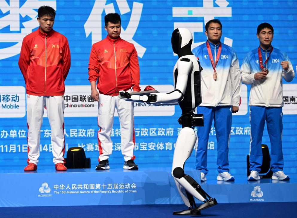 11月14日，人形機(jī)器人在拳擊男子92公斤級(jí)頒獎(jiǎng)儀式上手捧獎(jiǎng)牌。