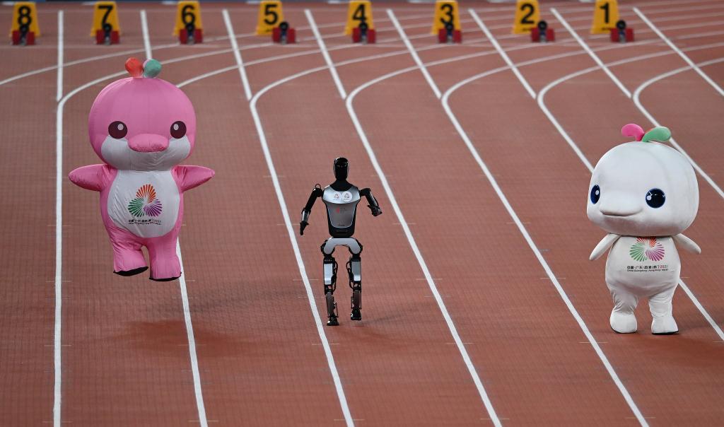11月17日，在田徑項目賽事開始前的暖場活動中，機器人和吉祥物喜洋洋、樂融融在廣東奧體中心體育場賽跑。