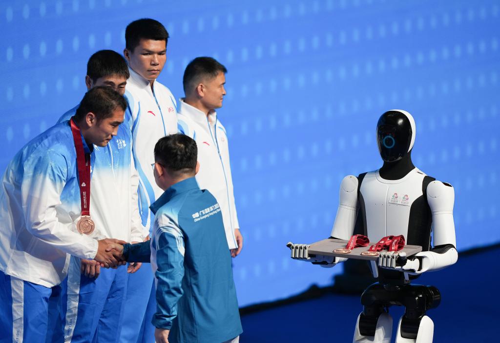 11月14日，人形機(jī)器人在拳擊男子92公斤級(jí)頒獎(jiǎng)儀式上為頒獎(jiǎng)嘉賓遞上獎(jiǎng)牌。