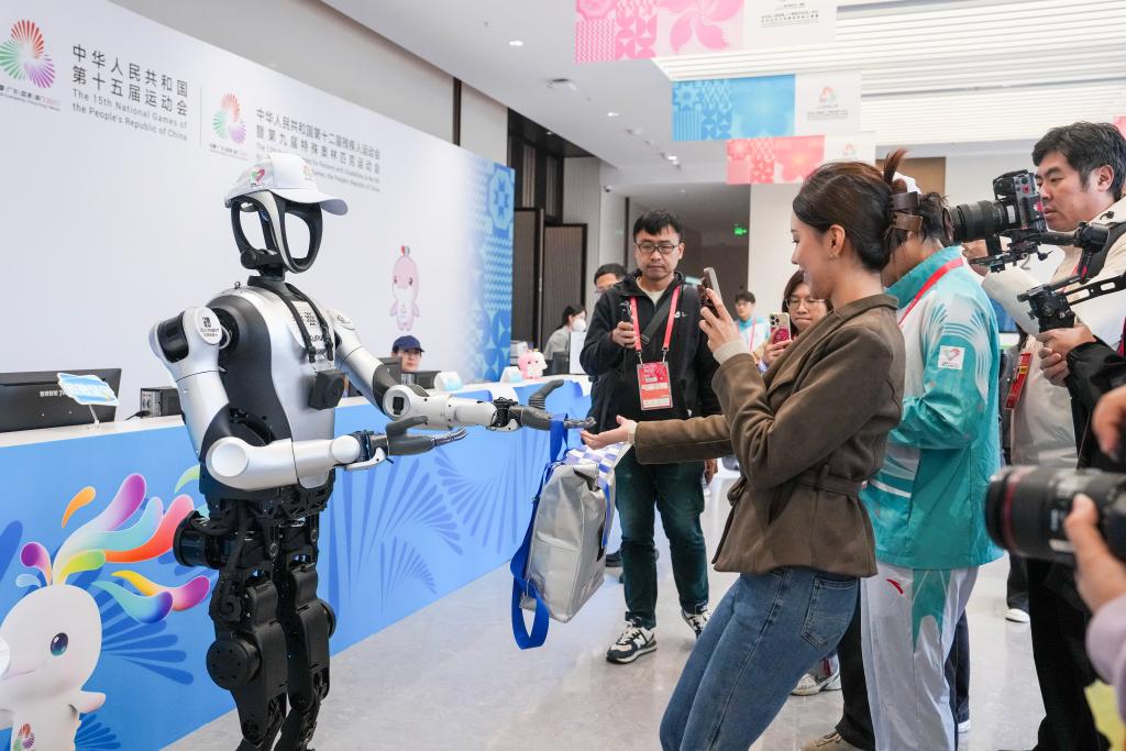 11月19日，人形機(jī)器人在深圳賽區(qū)分媒體中心為記者發(fā)放媒體包。