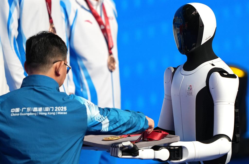 11月14日，人形機器人在拳擊男子92公斤級頒獎儀式上為頒獎嘉賓遞上獎牌。