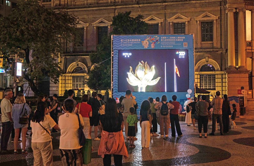 11月9日，第十五屆全國運動會開幕式在廣東奧林匹克體育中心舉行，這是群眾在澳門街頭觀看直播。新華社發（張金加 攝）