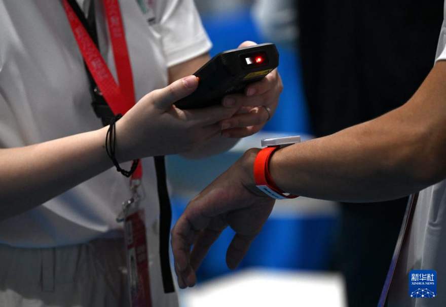 公路自行車賽參賽人員及車輛均需在比賽前裝上無線射頻識別系統（RFID）的設備及戴上連接全球定位系統的手環。圖為工作人員在掃描參賽人員的通關手環。