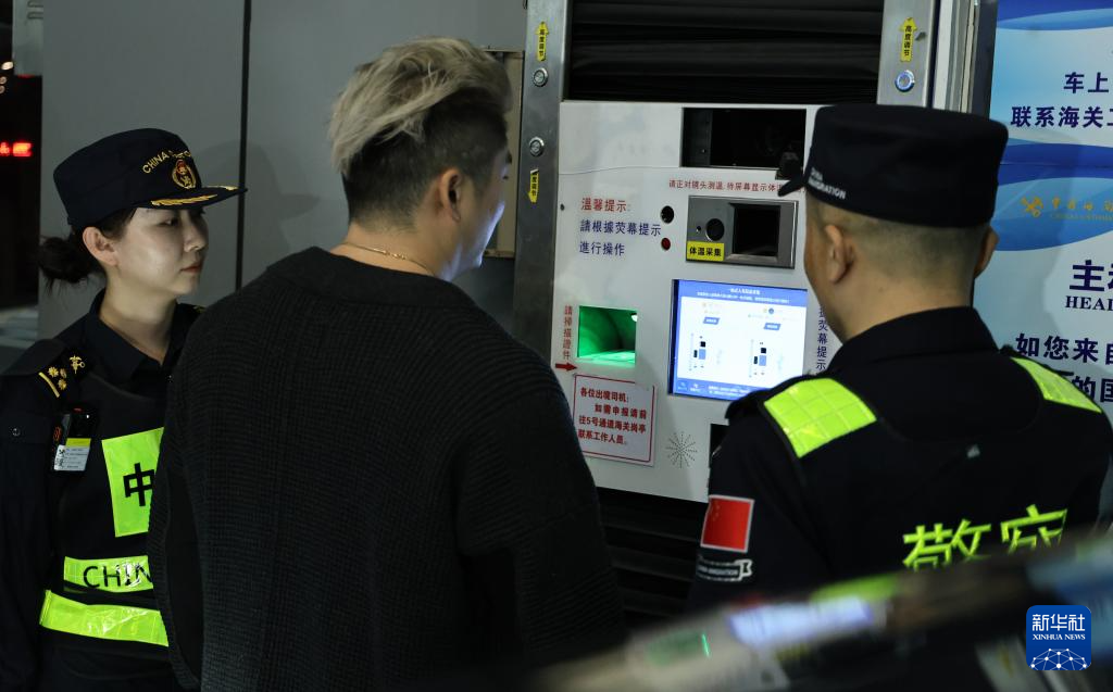 12月23日，“粵車南下”入境香港市區的首位通關車主彭先生（中）在“一站式”通道辦理通關手續。新華社記者 黃國保 攝