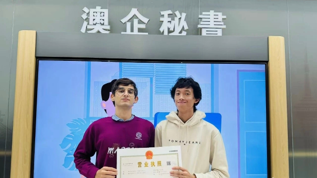 澳門(mén)青年陳葦楠與意大利伙伴馬丁在橫琴粵澳深度合作區(qū)政務(wù)服務(wù)中心的“澳企秘書(shū)”專(zhuān)窗前并肩而立