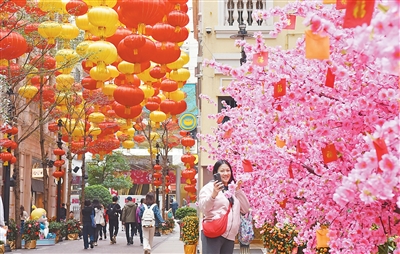 圖為一名女士在香港利東街與新春裝飾“桃花樹(shù)”自拍合影。新華社記者 陳 鐸攝