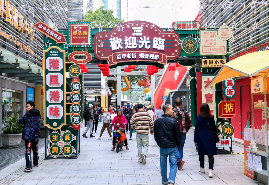 憑借毗鄰香港的獨特區(qū)位，大灣區(qū)內(nèi)地城市正將港式生活美學與跨境消費體驗深度融入城市肌理，打造“港風港味”的文旅消費新場景。在沙頭角港式風情街區(qū)，建筑風貌、商鋪招牌、街頭視覺與聽覺元素高度還原了經(jīng)典港式街區(qū)氛圍，匯聚國際美妝、潮流服飾、港式茶餐廳、跨境商品等特色商戶，并融入魚燈舞等非遺元素，滿足了消費者對港式風情與跨境購物的一站式體驗需求，是深港融合文化在消費領(lǐng)域的生動體現(xiàn)，成為網(wǎng)紅打卡與消費熱點。